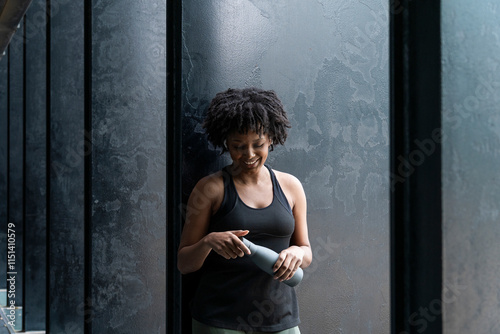 Smiling woman holding bottle and standing near black door photo