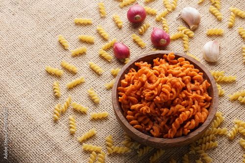 Spicy fried small macaroni crackers, on a brown cloth background, flat lay or top view, with studio lighting