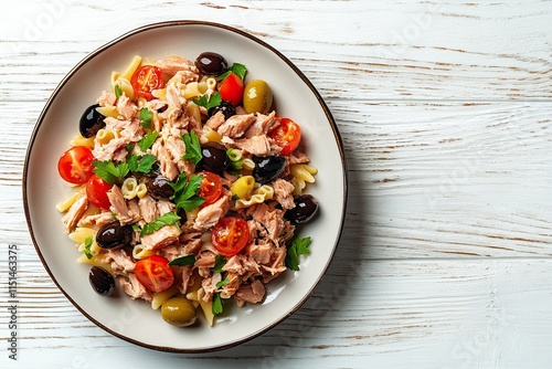 Pasta fredda con tono, pomodorini and olives, pasta salad with canned tuna, cherry tomatoes and olives on a plate on a white wooden background. 