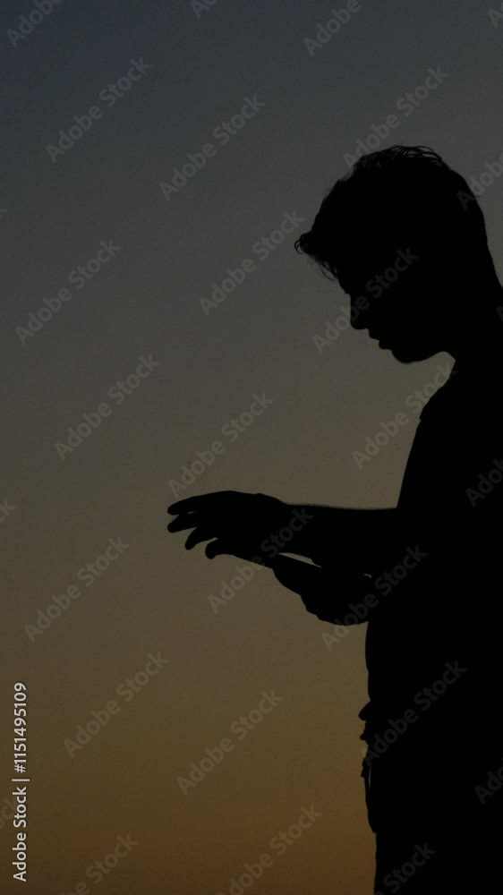 Silhouette of teenager smoking while using phone Silhouette of teenager smoking while using phone