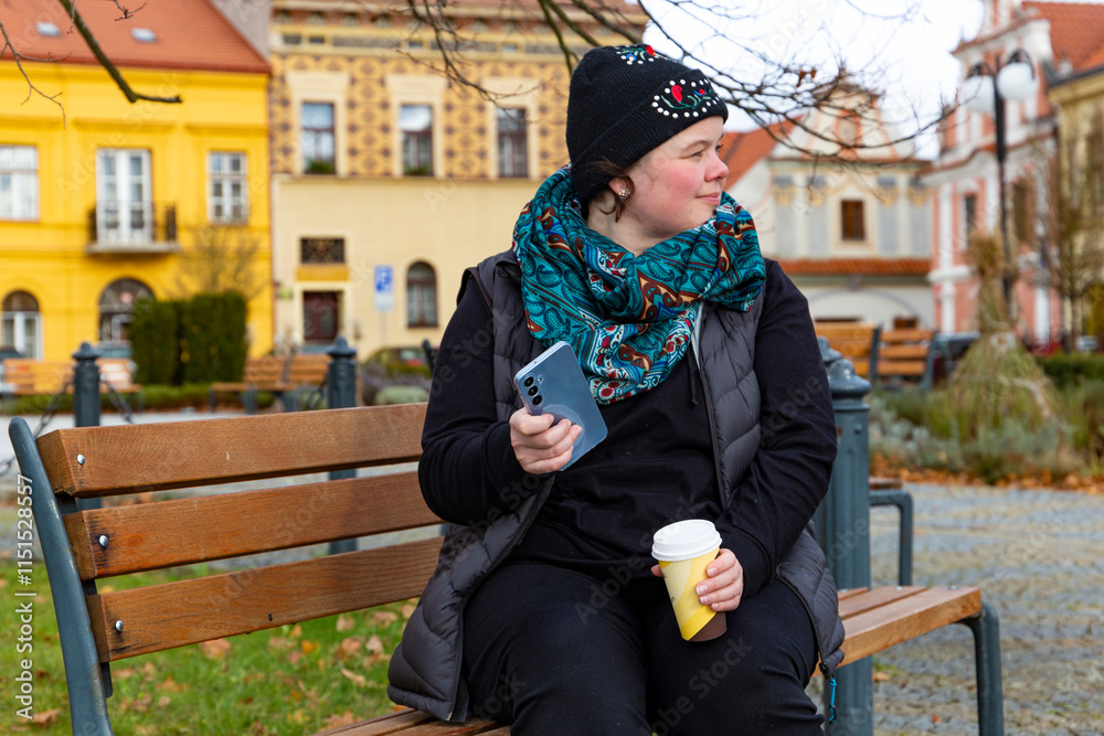A woman walking through an autumn city and drinking coffee.
