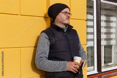 Obraz na płótnie A man with a cup of coffee walking through an autumn city. w salonie