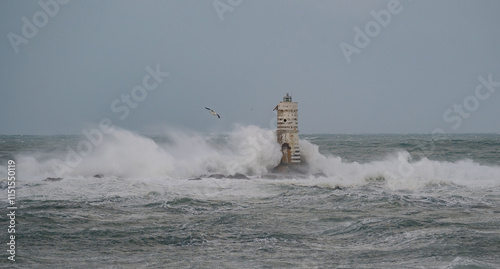 white and black striped lighthouse surrounded by stormy sea waves photo