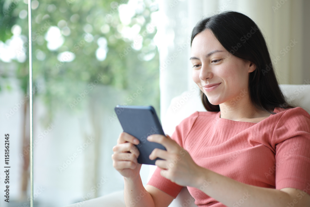 Satisfied asian woman reading ebook at home Satisfied asian woman reading ebook at home
