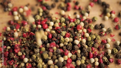 allspice in the form of round balls of different colors pour on a cutting board in slow motion. Using peppercorns for cooking. Spicy ingredients for meat and vegetables photo