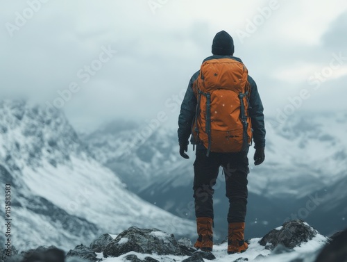 man with orange backpack hiking in the mountains on a snowy day