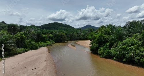 Drone footage of Plai Wha river surrounded by green forest and cloudy sky in Thailand photo