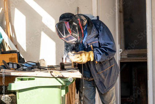 Man welder working on construction site, worker builder making weld photo