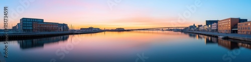 A beautiful sunset over a calm body of water. The sky is a mix of orange and pink hues, creating a serene and peaceful atmosphere. The water is still, reflecting the colors of the sky