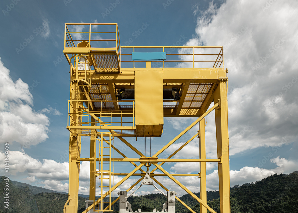 View of Yellow gantry overhead crane control watergate and water in the dam between the hills at The Khun Dan Prakan Chon Dam, Nakhon Nayok Province, Thailand, Crane overhead beam machine with sky.