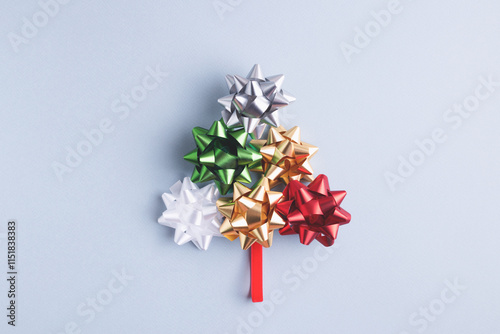 Christmas and New Year, conceptual composition. Creative fir tree made of holiday bow and ribbon on gray-blue background. Top view, copy space.