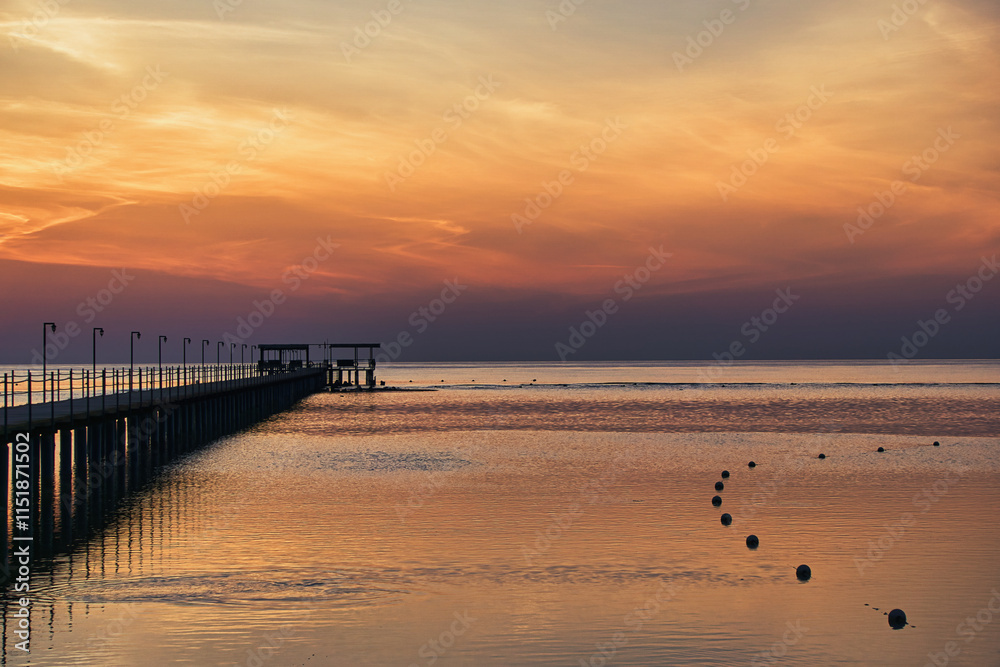 Beautiful sunrise on Red Sea, Marsa Alam, Egypt, outline of the boat, umbrellas, beach, chillout in the morning. Silhouettes of people against the background of sunrise, A jetty extending into the sea Beautiful sunrise on Red Sea, Marsa Alam, Egypt, outline of the boat, umbrellas, beach, chillout in the morning. Silhouettes of people against the background of sunrise, A jetty extending into the sea