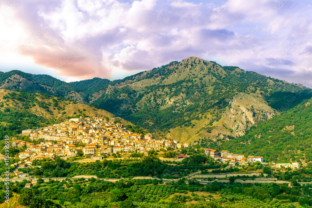Fototapeta premium amazing mountain landscape with old yellow italian town among green beatiful mountains and cloudy sky above