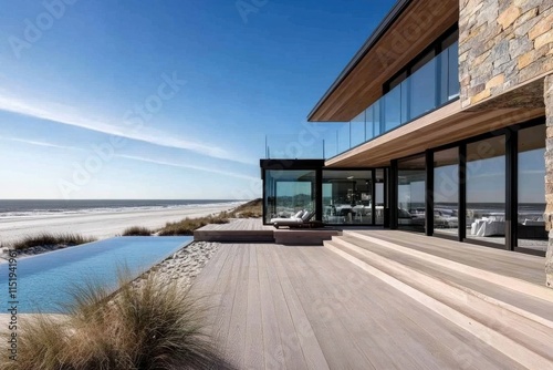 An elegant modern home beautifully situated on a dune, with expansive glass walls offering stunning views of the ocean waves and luxurious outdoor living space. photo