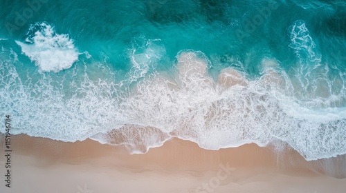 Aerial panorama of a sunlit turquoise ocean coastline with gentle waves rolling onto a pristine sandy beach on a clear summer day