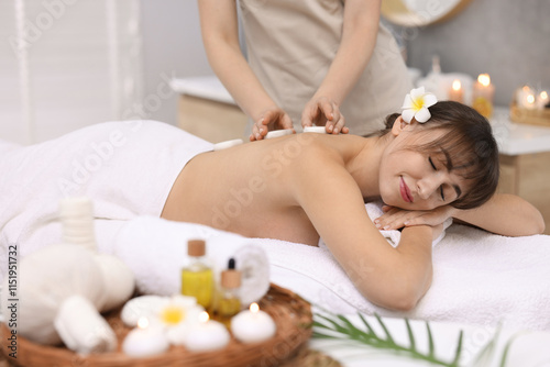 Young woman receiving hot stone massage in spa salon