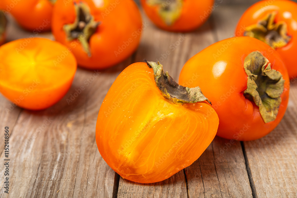 Persimmon on textured wooden background. Persimmon fruit. A piece of ripe, juicy, sweet persimmon fruit. Vegan. Orchard. Close-up. Space for text. Copy space. Persimmon on textured wooden background. Persimmon fruit. A piece of ripe, juicy, sweet persimmon fruit. Vegan. Orchard. Close-up. Space for text. Copy space.