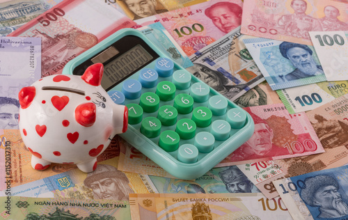 Calculator and piggy bank against the background of different banknotes from different countries of the world photo