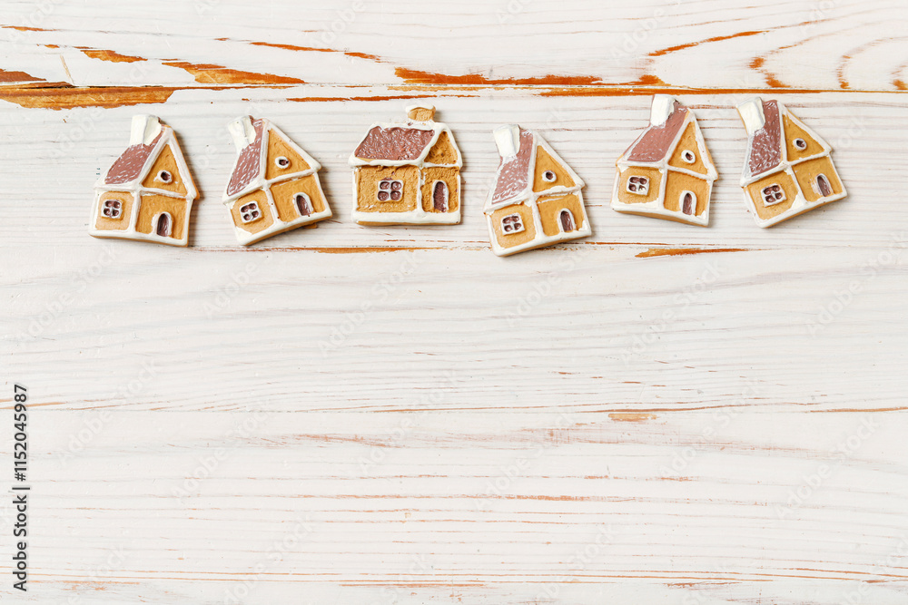 Classic Christmas backgound with tiny gingerbread cookies in house shape on white wooden background.