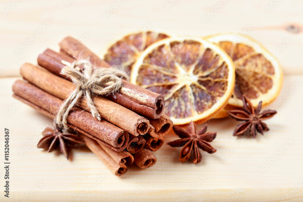Cinnamon sticks and dried oranges on wooden table.