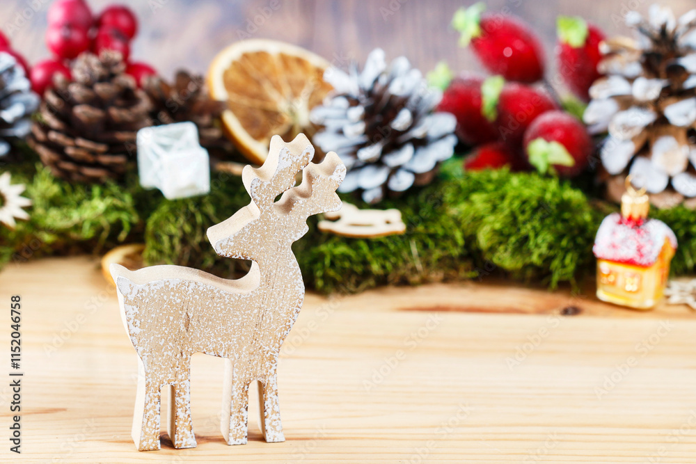 Wooden deer figurine in front of classic Christmas garland, copy space.