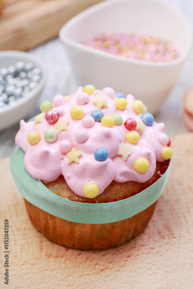 Pink muffins decorated with colorful sprinkles.