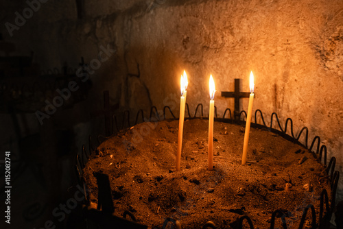 Candles in church. Religious concept. Candles in a tray with sand on the background of cross photo