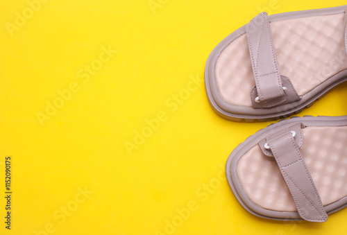 Women's leather sandals on yellow background. Summer shoes. Top view. Copy space