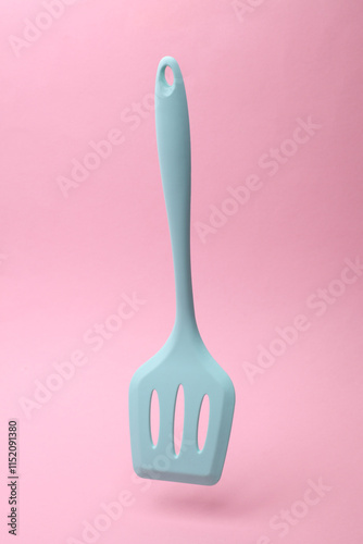 Silicone kitchen spatula floating on a pink background photo