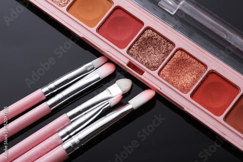 Makeup brushes with eye shadow palette on black background