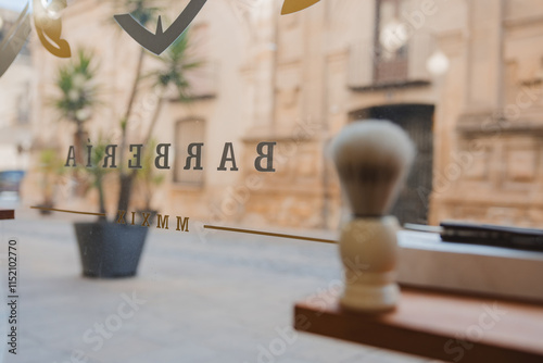 A window of a barbershop with a barber's brush on the window sill