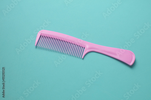 Pink plastic comb on mint green background.