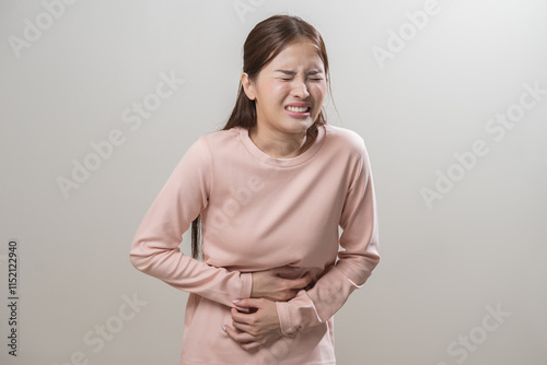 Flatulence asian young woman intolerance hand in stomach ache, suffer from food poisoning, abdominal pain and colon problem, gastritis or diarrhoea when at home. Patient belly, abdomen or inflammation photo