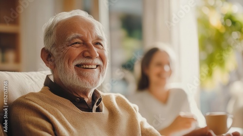 Smiling elderly man enjoying a warm moment with family in a cozy living room filled with natural light, sharing laughter and joy during a relaxed afternoon together