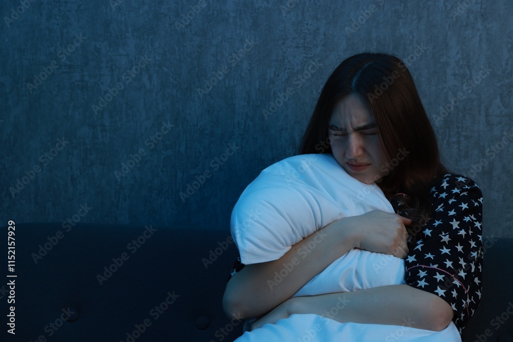 Obraz premium Fear of darkness. Scared young woman hugging pillow on couch indoors at night, space for text