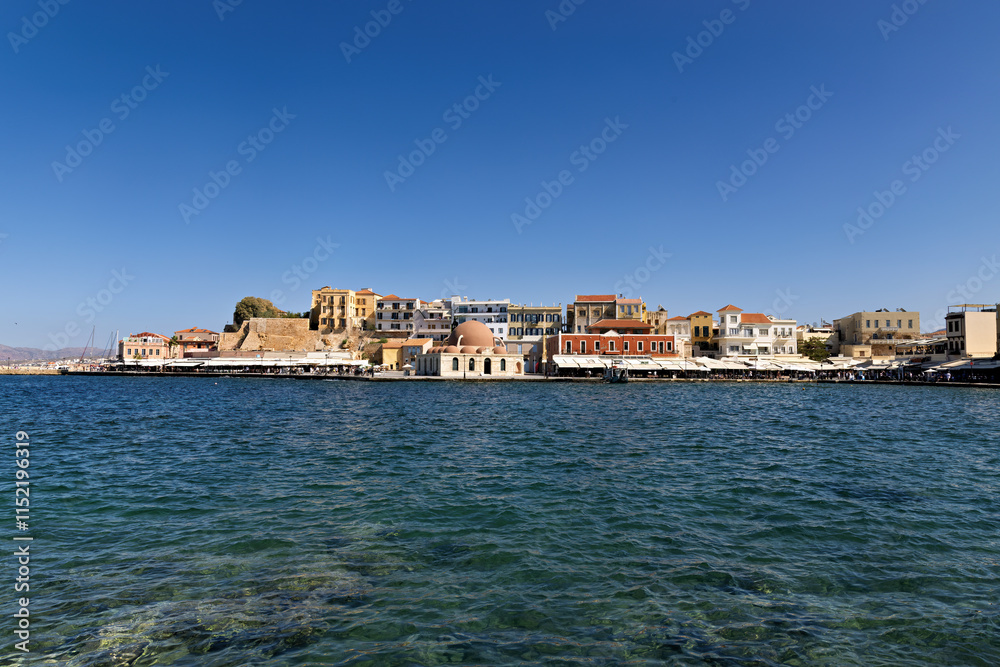 Chania, old Venetian harbor with Hasan Pasha Mosque and row of shops with cafes on Crete, Greece Chania, old Venetian harbor with Hasan Pasha Mosque and row of shops with cafes on Crete, Greece