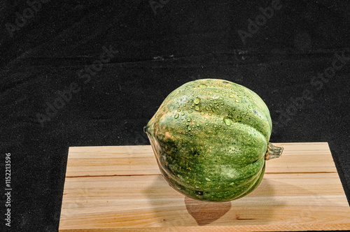 Front view, close distance of, a washed acorn squash, on a wood board with black background