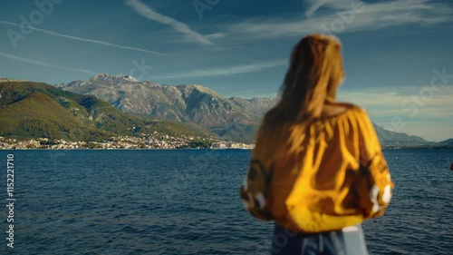 Woman silhouette exploring serene sea views beneath majestic mountains of Lovcen in Montenegro