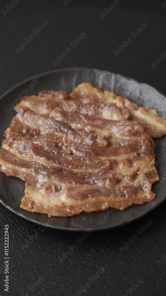 Crispy fried pork bacon sliced with salt, spices and herbs on dark concrete background Crispy fried pork bacon sliced with salt, spices and herbs on dark concrete background