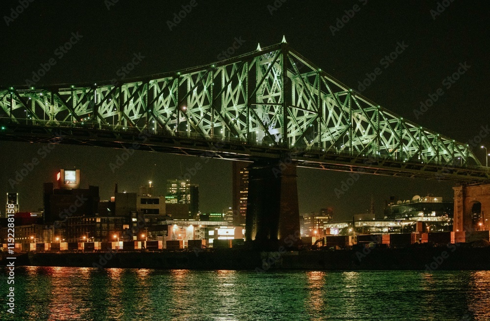 side view of a green suspended bridge as seen from the river in summer at night
