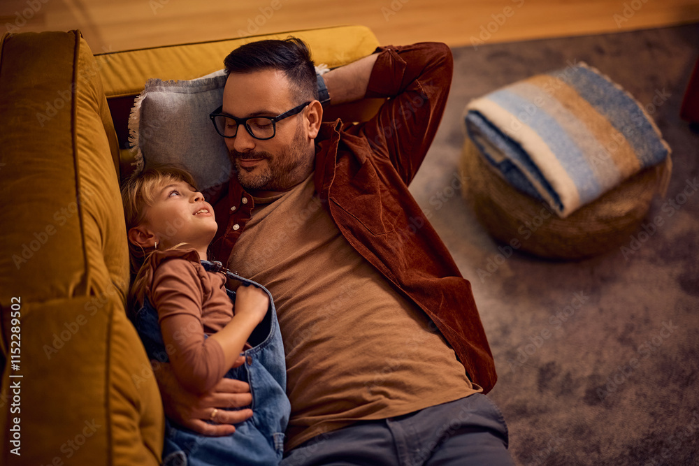 Fototapeta premium Above view of smiling father and daughter relaxing on sofa.