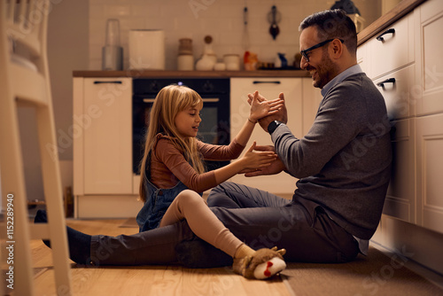 Happy father and daughter playing hand clapping game at home. photo