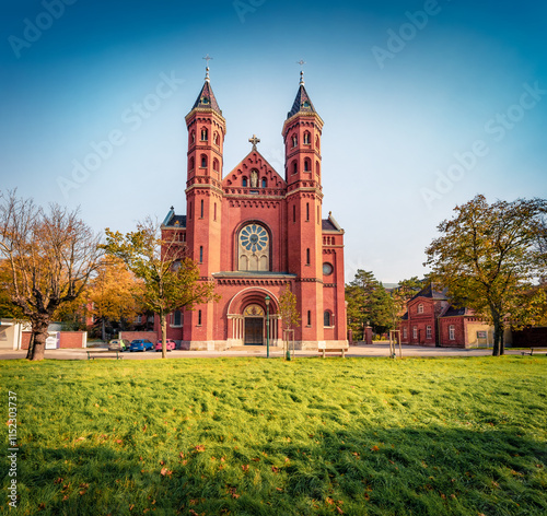 Colorful summer view of red briks Catholic Church of the Holy Spirit. Exciting morning cityscape of Maria Enzersdorf town, Austria, Europe. Traveling concept background. photo