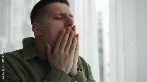 A man covers his mouth with his hand when he yawns.
The man yawns from fatigue.
Bad dream.
The man did not get enough sleep and yawns