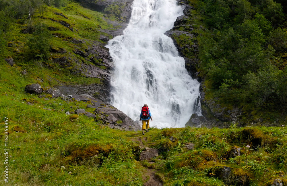 A Serene Hiker standing next to a Majestic Waterfall in a Beautiful Lush Green Landscape A Serene Hiker standing next to a Majestic Waterfall in a Beautiful Lush Green Landscape