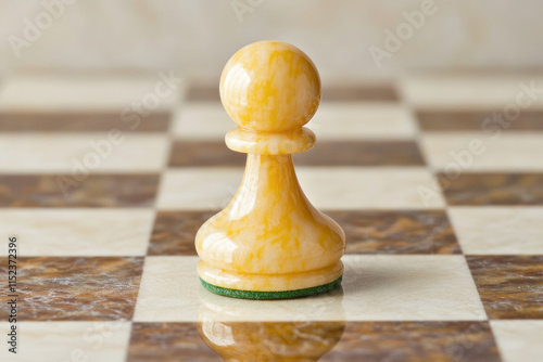 Yellow marble chess pawn on brown and white checkered board photo