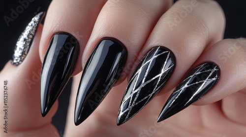 Elegant black and silver stiletto nails with intricate designs showcased on a hand