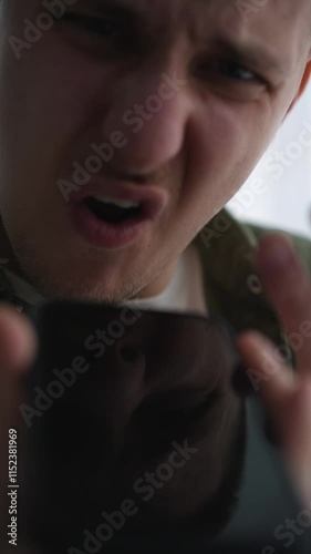 Angry man talking on the phone very emotionally.
A man is talking on speakerphone.
Dissatisfied guy shouting at his interlocutor on the phone