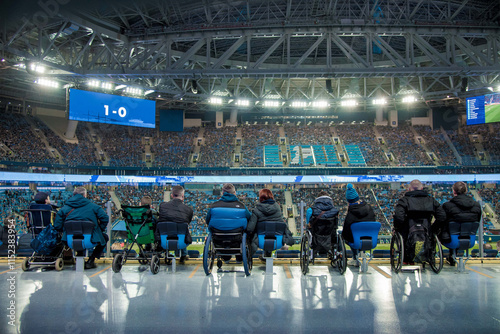 Football match soccer field, fans disabled person sit stands, players run ground