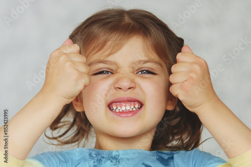 Canvas Print Portrait of cheerful funny girl with cranky face looking to right on gray backgr